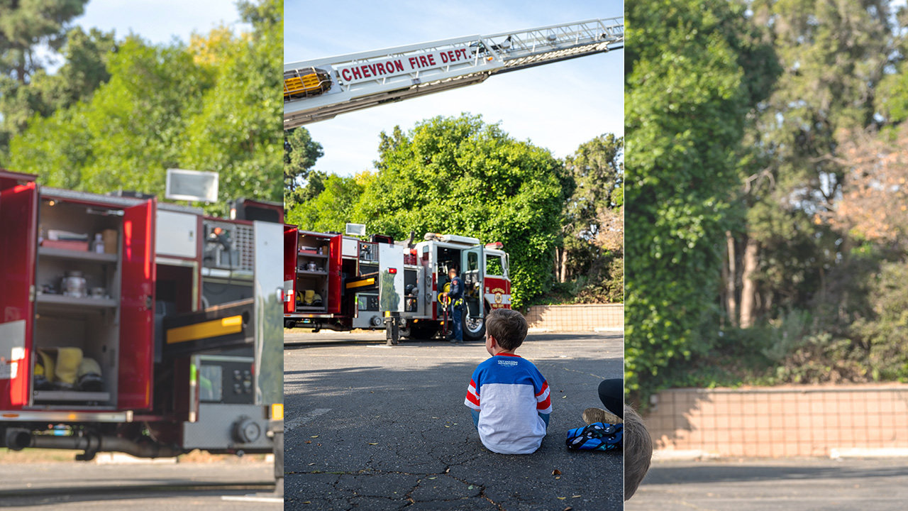 a child sitting on the ground looking at a fire truck